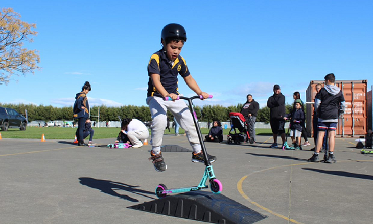 Child hopping over a ramp with a scooter