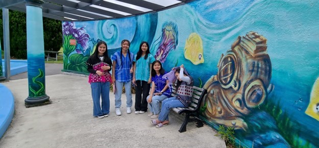 Group of young women standing by an aquarium related artwork