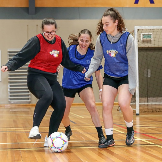 Young women playing football on an indoor court