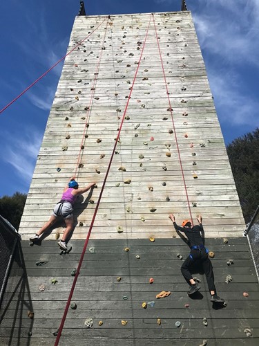 Two young women climbing a rockwall