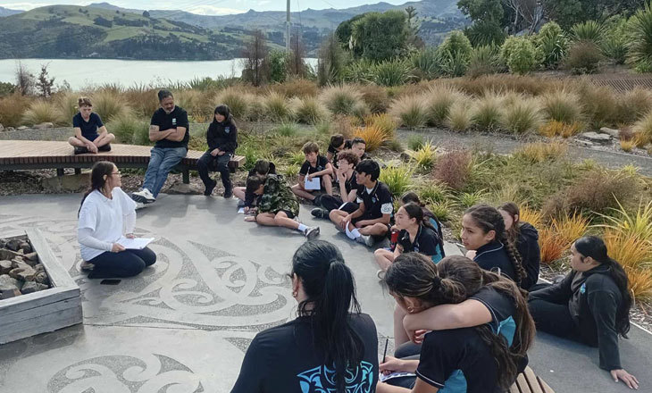 A group of sitting outside on a koru patterned sealed surface