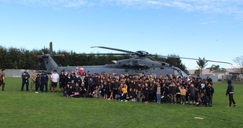 People standing in front of a helicopter on a grass lawn