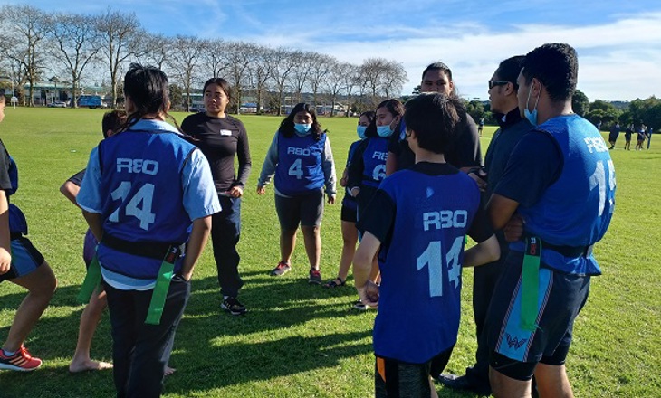 Group of rangatahi/youth sanding in a circle on a field