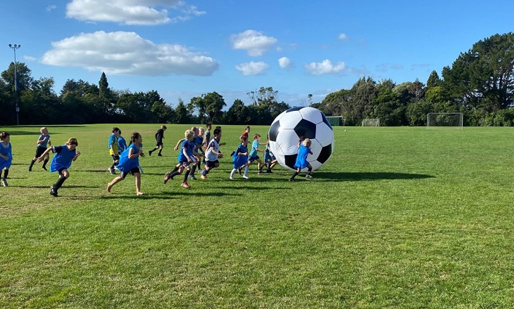 kids running after a giant ball in a park