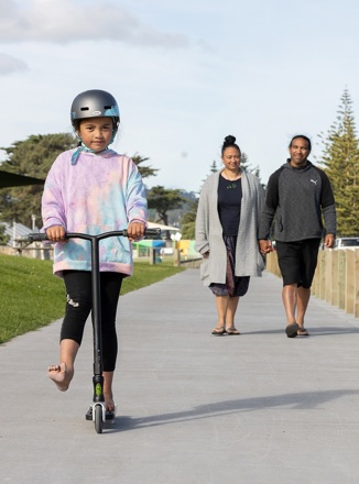 Parents walking with their child outside on a scooter