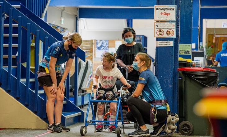 Climbing trainers assisting a child at a climbing gym