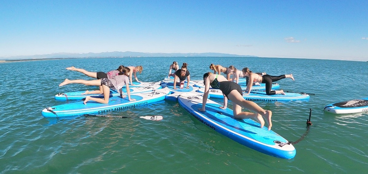 Group of young women doing a yoga pose on a SUP